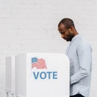 african american citizen voting near stand with vote lettering