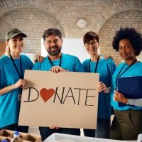 Diverse volunteers inviting people to donate to charity and looking at camera.